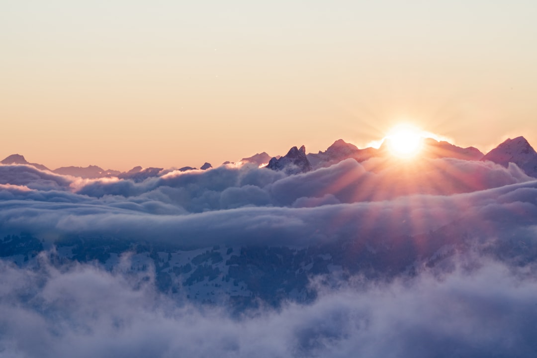 Photo by Livia The sun is setting over the clouds in the mountains